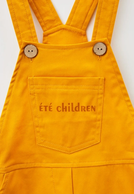 Комбинезон из хлопка горчичного цвета и лого 